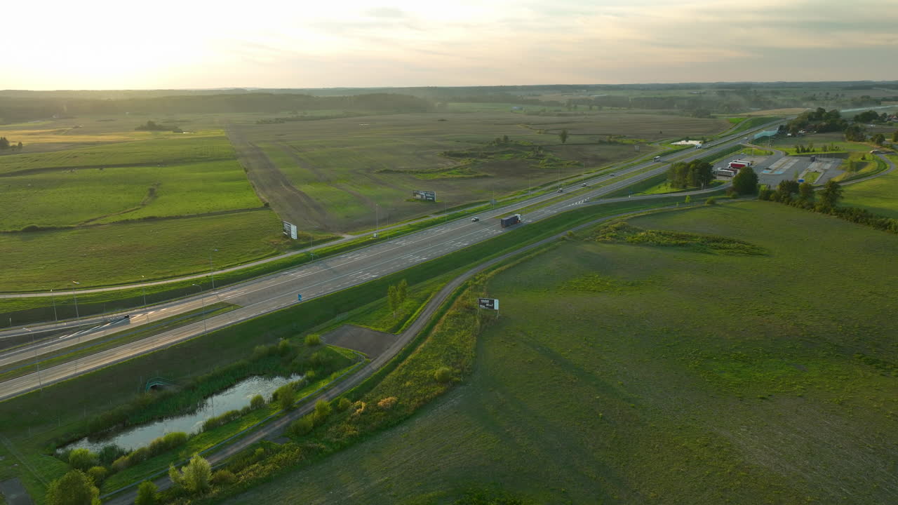 광활 한 야외 들 과 광고판 으로 둘러싸인 차량 과 함께 해 가 지는 고속도로 의 공중 전망, 시골 의 저녁 풍경 을 포착 하는 것