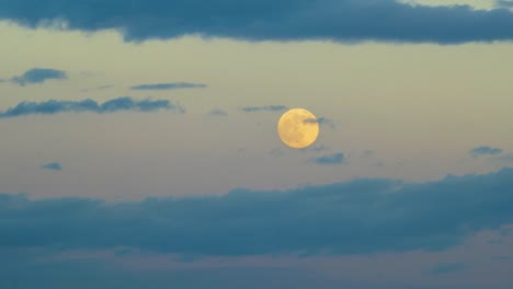 full moon rises behind the sunset clouds timelapse