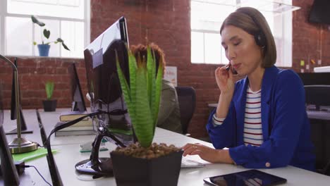 diversos colegas de negocios masculinos y femeninos con auriculares sentados en escritorios haciendo videollamadas