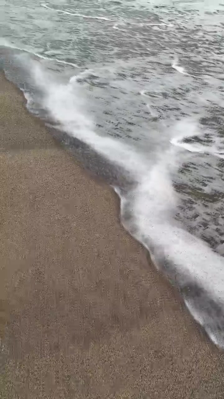 Dolci onde dell'oceano che si ritirano su una spiaggia di sabbia scura.
