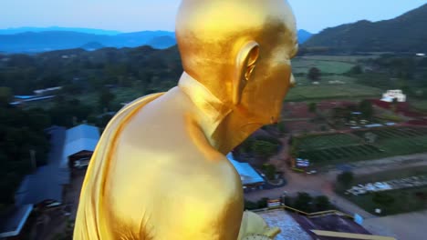 primer plano aéreo de 4k de la estatua dorada de luang pu thuat más grande del mundo rodeada de montañas de khao yai al amanecer en tailandia