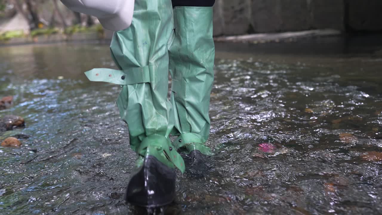 человек в ботинках для дождя, плывущий по ручью.