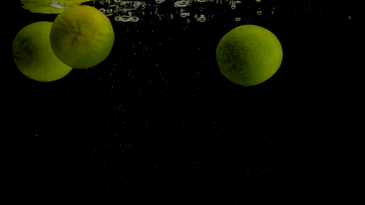 лима падает в воду на черном фоне. яркое видео высокого качества