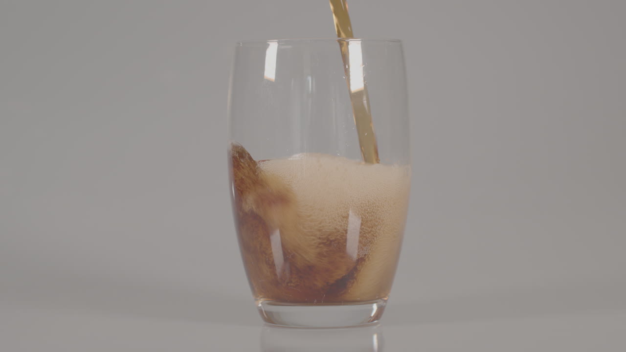 Cola versata in un bicchiere su sfondo bianco da studio