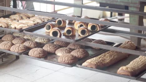 close-up of multiple trays filled with assorted baked pastries cooling on racks inside a bakery