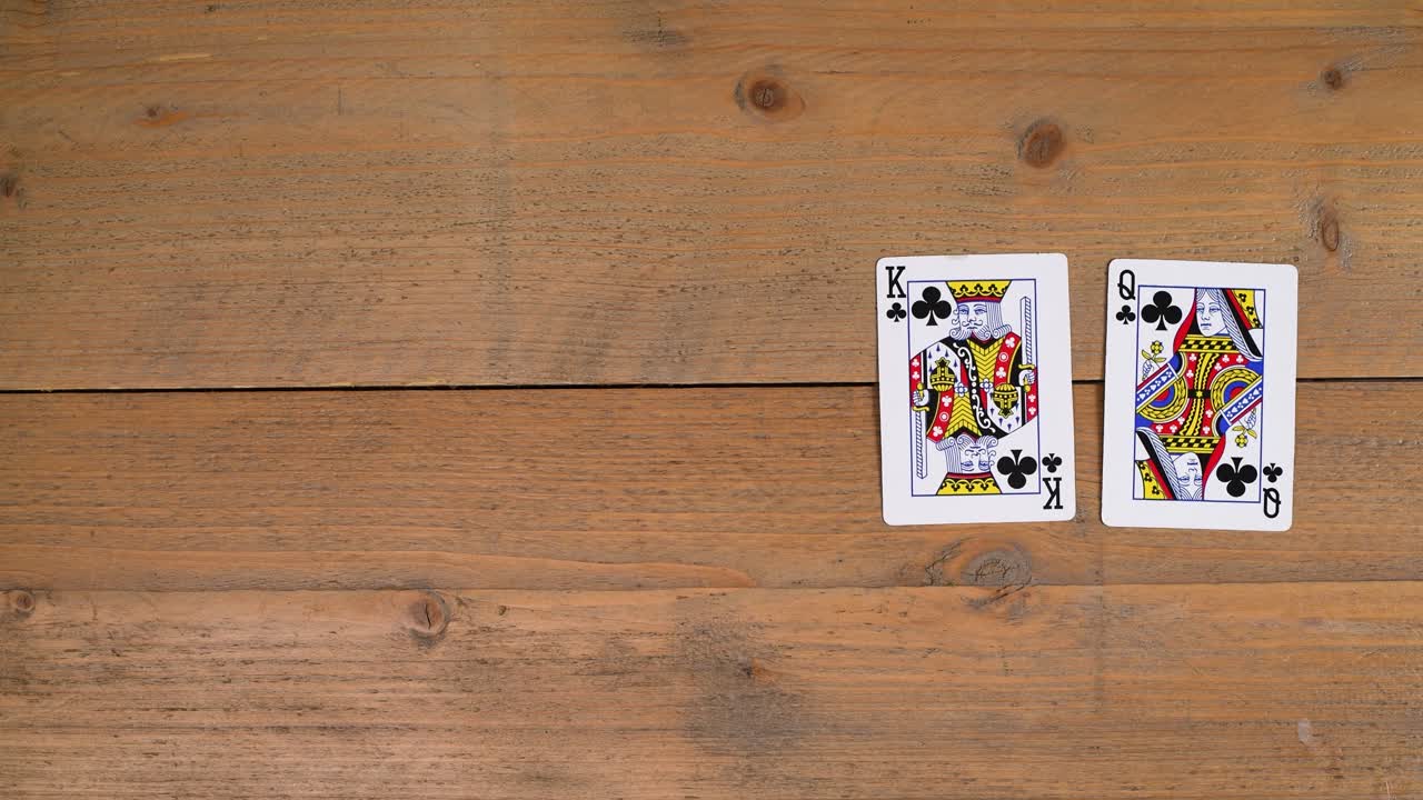 A person laying out a royal flush chance on a wooden table to educate the viewer on how to play poker