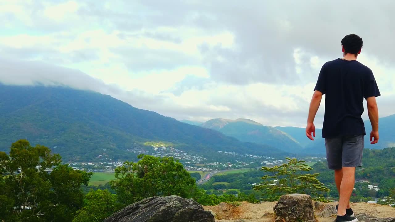 un hombre caminando para disfrutar del hermoso paisaje, con vistas a la pacífica ciudad de queensland, australia - toma amplia