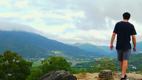 a man walking up to enjoy beautiful scenery, overlooking the peaceful city of queensland, australia - wide shot