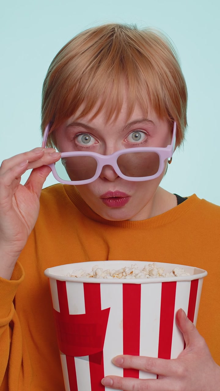 Woman in 3d glasses eating popcorn and watching interesting tv serial sport game film online movie