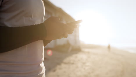 Man,-phone-and-hands-typing-on-beach