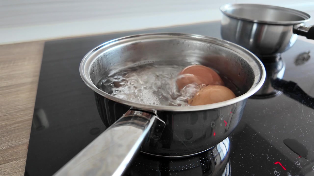 Uova che bollono in pentola sul fornello della cucina