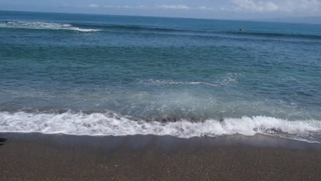 在熱帶海灘上的夏天場景,海浪在滾動,一個人在遙遠處游泳