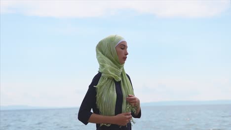 woman in hijab running on the beach