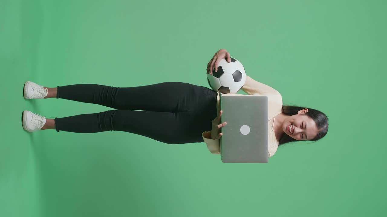 mujer con una pelota de fútbol y una computadora portátil