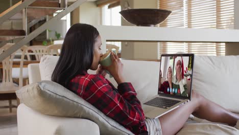 Mujer-De-Raza-Mixta-Usando-Una-Computadora-Portátil-En-Un-Video-Chat-Con-Amigos-Durante-La-Navidad-En-Casa