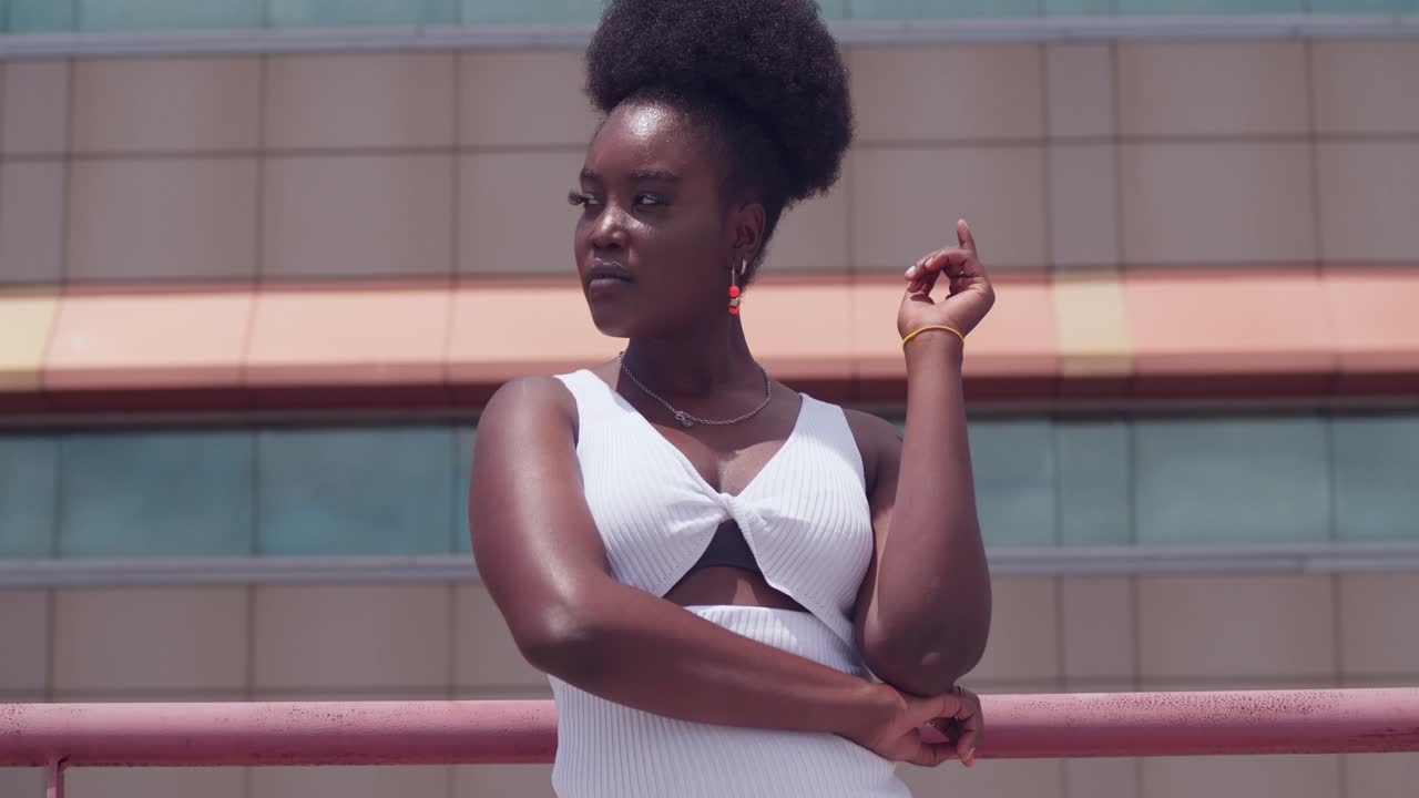 A young black girl in a white dress is on a rooftop, taking in the city view
