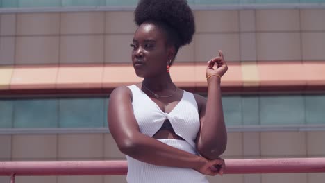 a young black girl in a white dress is on a rooftop, taking in the city view