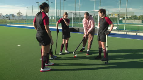 female hockey team strategizing on field during sunny practice session