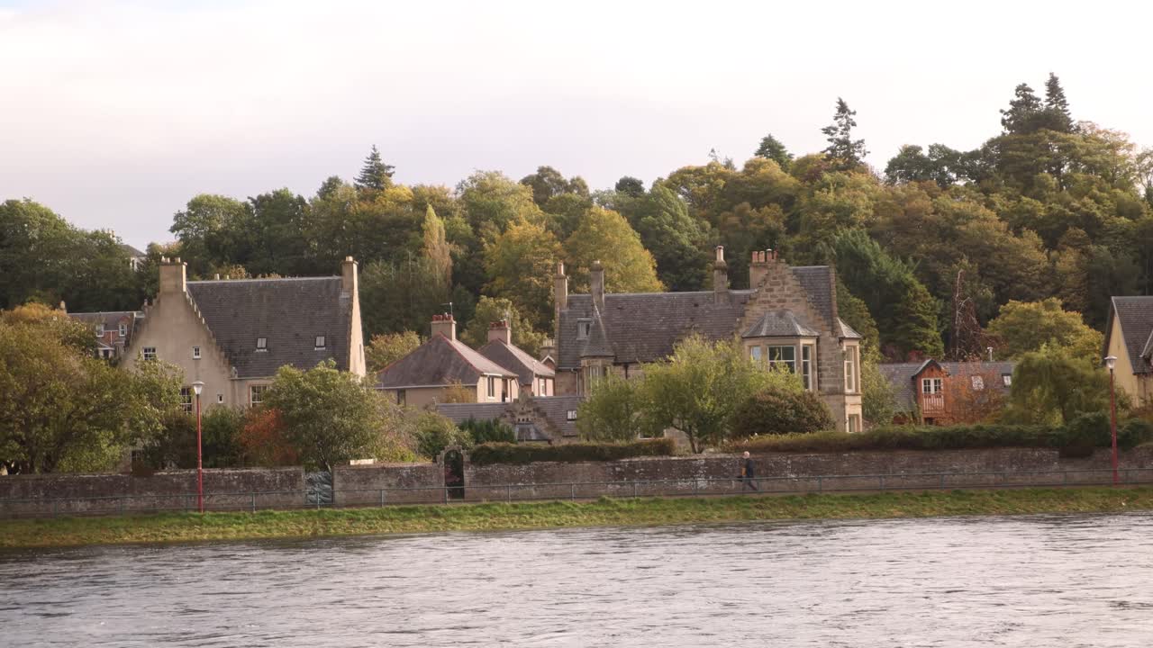 Persone che camminano lungo il lungofiume costeggiando belle case a Inverness, Scozia, nelle Highlands.