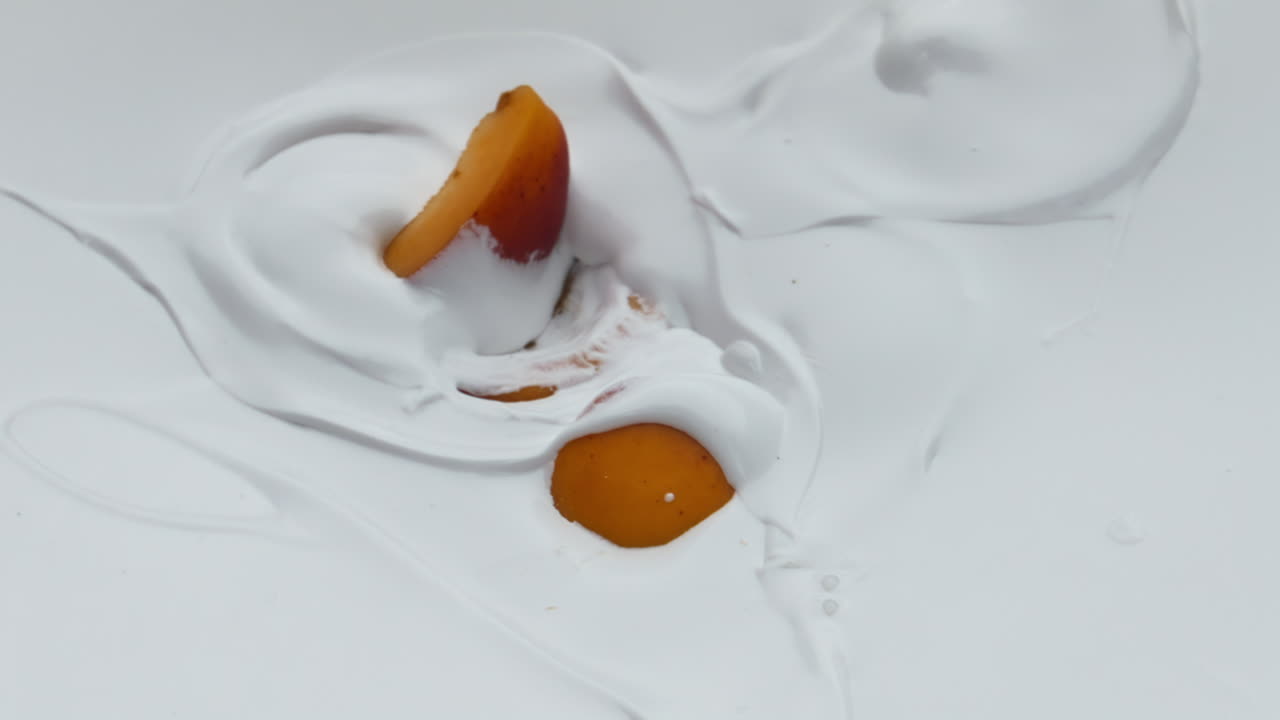 Sliced apricot falling yogurt in super slow motion close up. Natural breakfast.