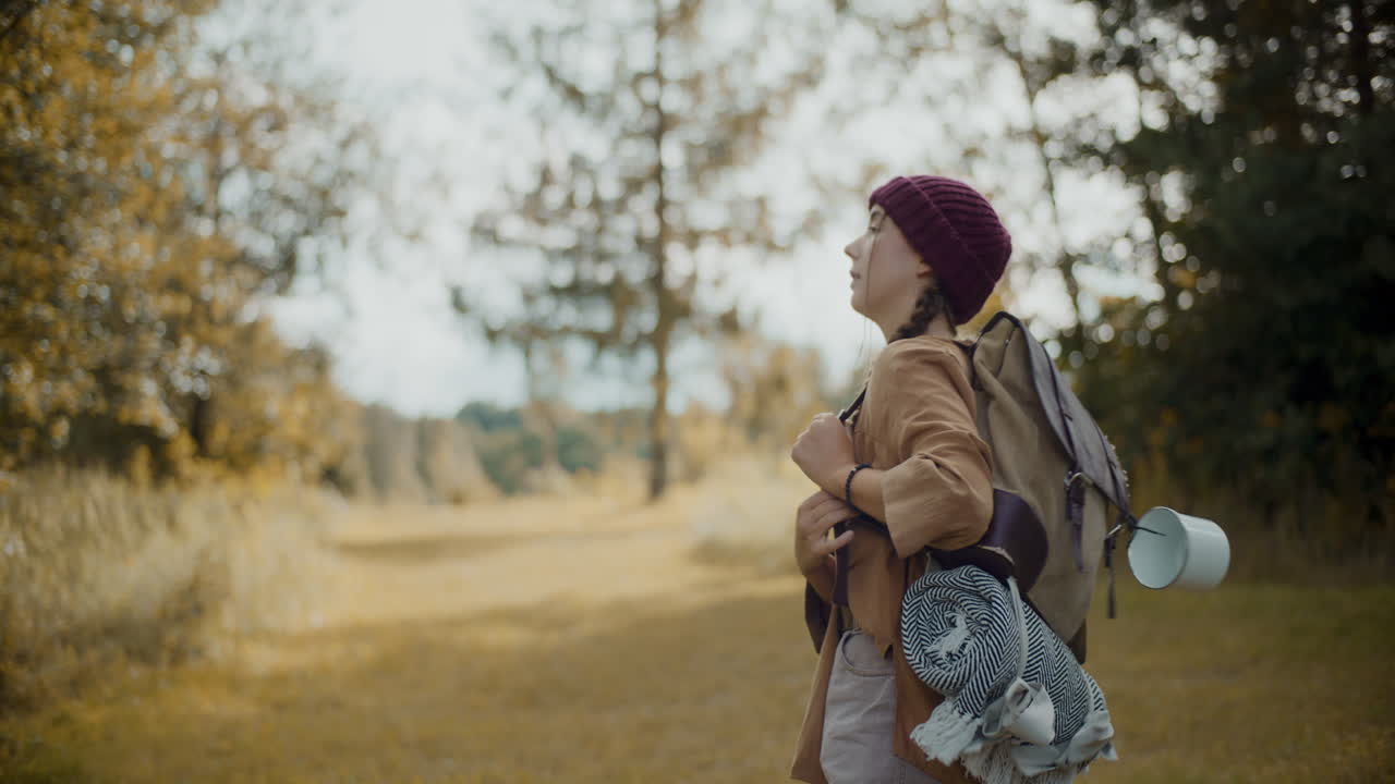 Woman with backpack walking on grass in forest