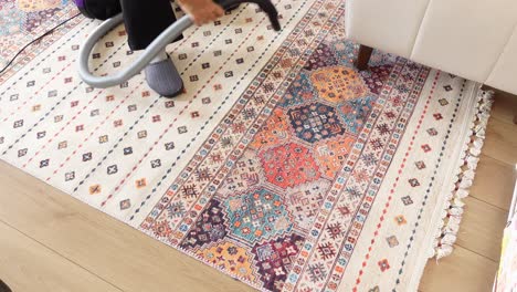 woman vacuuming a colorful rug in her living room