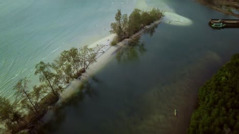 Aerial-view-slowly-revealing-a-tropical-island-during-the-morning-hours-in-Thailand,-Koh-Kood,-visible-sandy-beach-and-some-rock-formation-,-there-are-also-mountains-in-the-distance