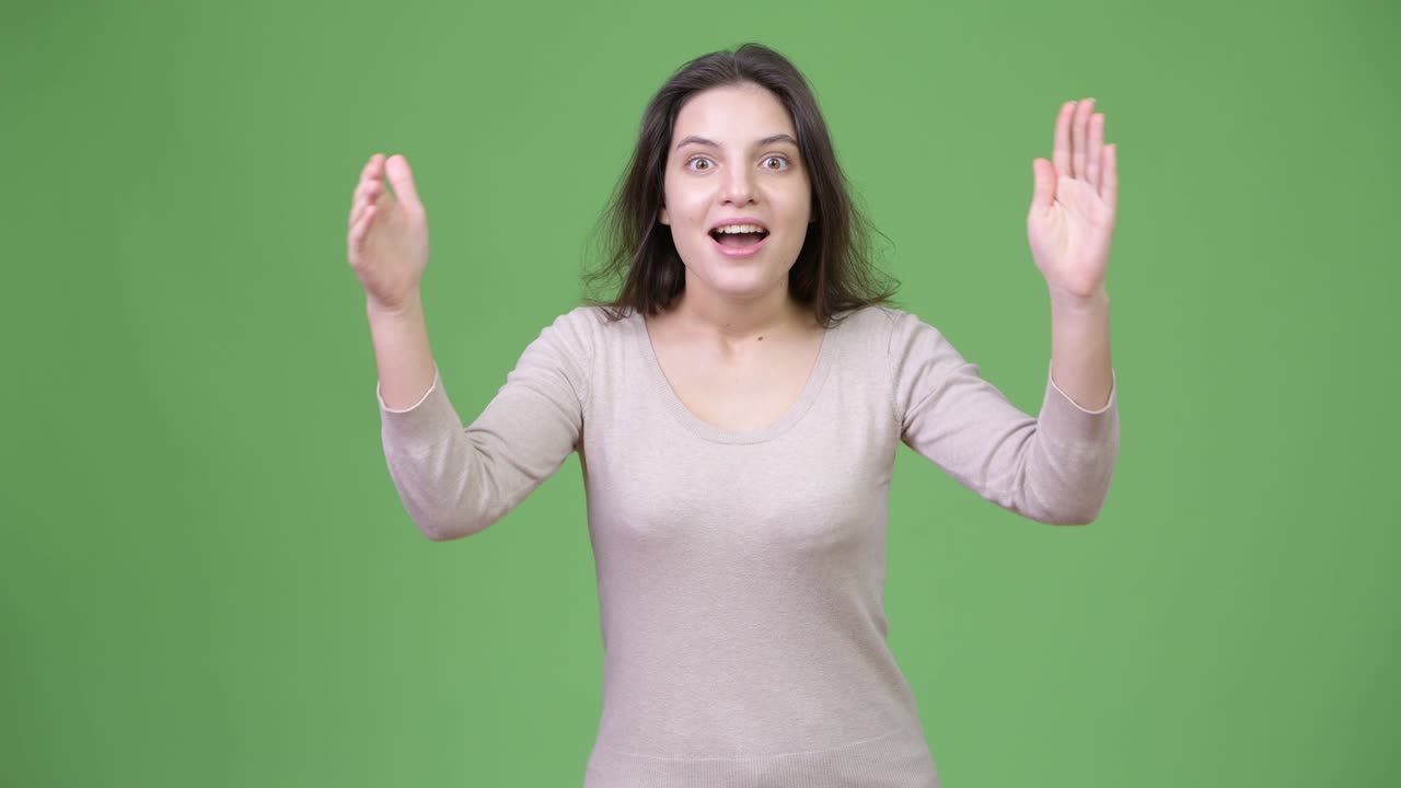 Giovane donna bellissima che applaude su sfondo verde.