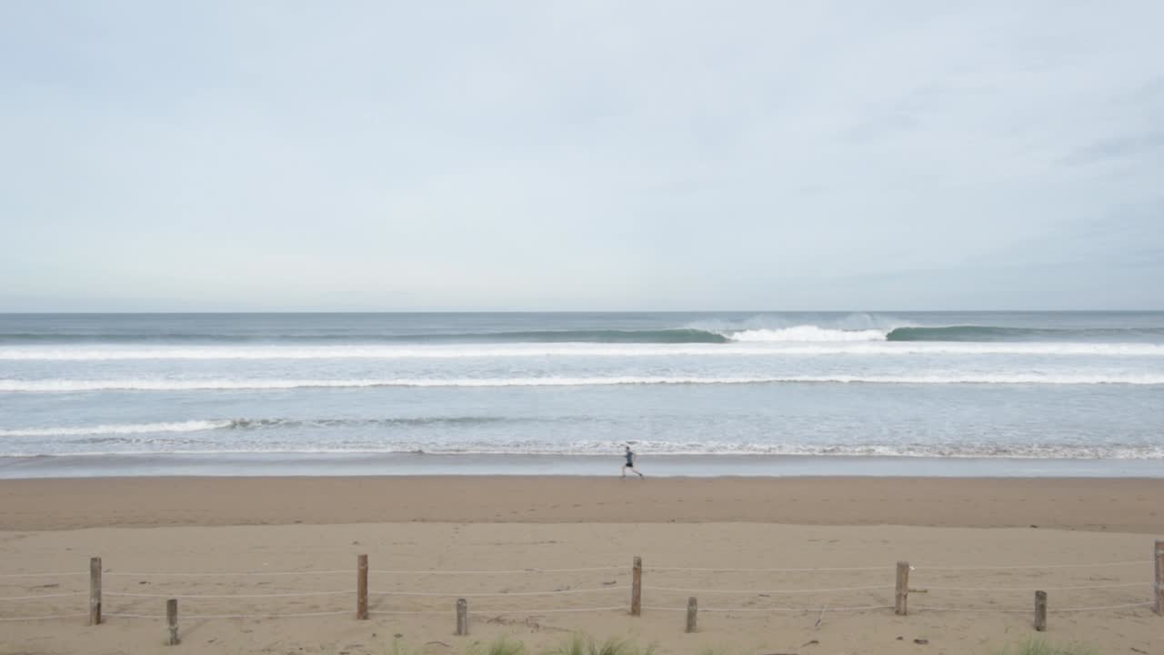 deportista en ropa activa corriendo en una playa solitaria