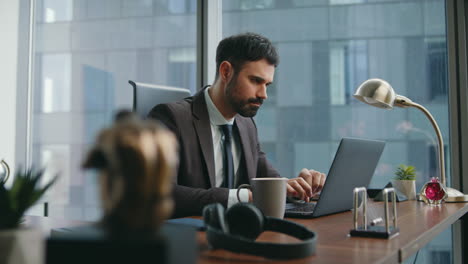 serious businessman solving issues working on modern laptop at workplace closeup