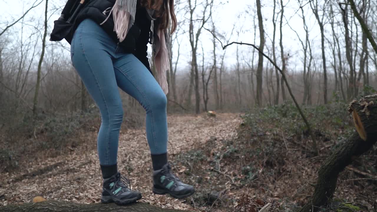 Young caucasian woman photographer with hiking shoes walking and balancing on cut tree laying on leaf covered road in forest, SLOW MOTION