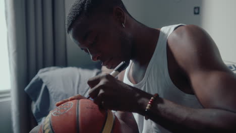 african american athlete writing a sign on basketball