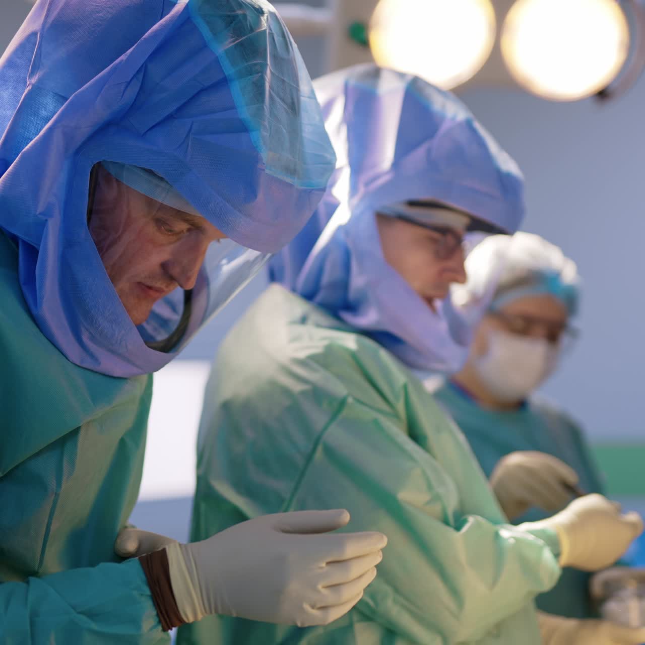 Group of medics wearing special protective helmets starting an operation. Orthopedic surgery in modern hospital