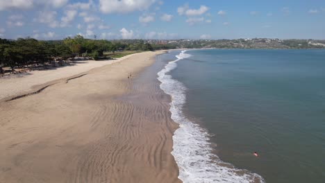 aerial video on jimbaran beach at bali, denpasar, indonesia during a sunny day with calming sea waves