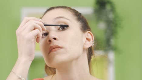 young woman applying mascara to her eyelashes.