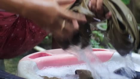 mujer indonesia lavando ropa al lado del baño