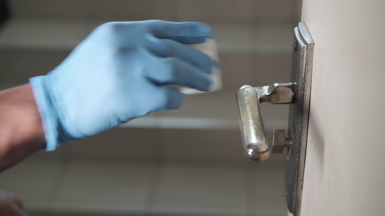 limpieza de un mango de la puerta con desinfectante