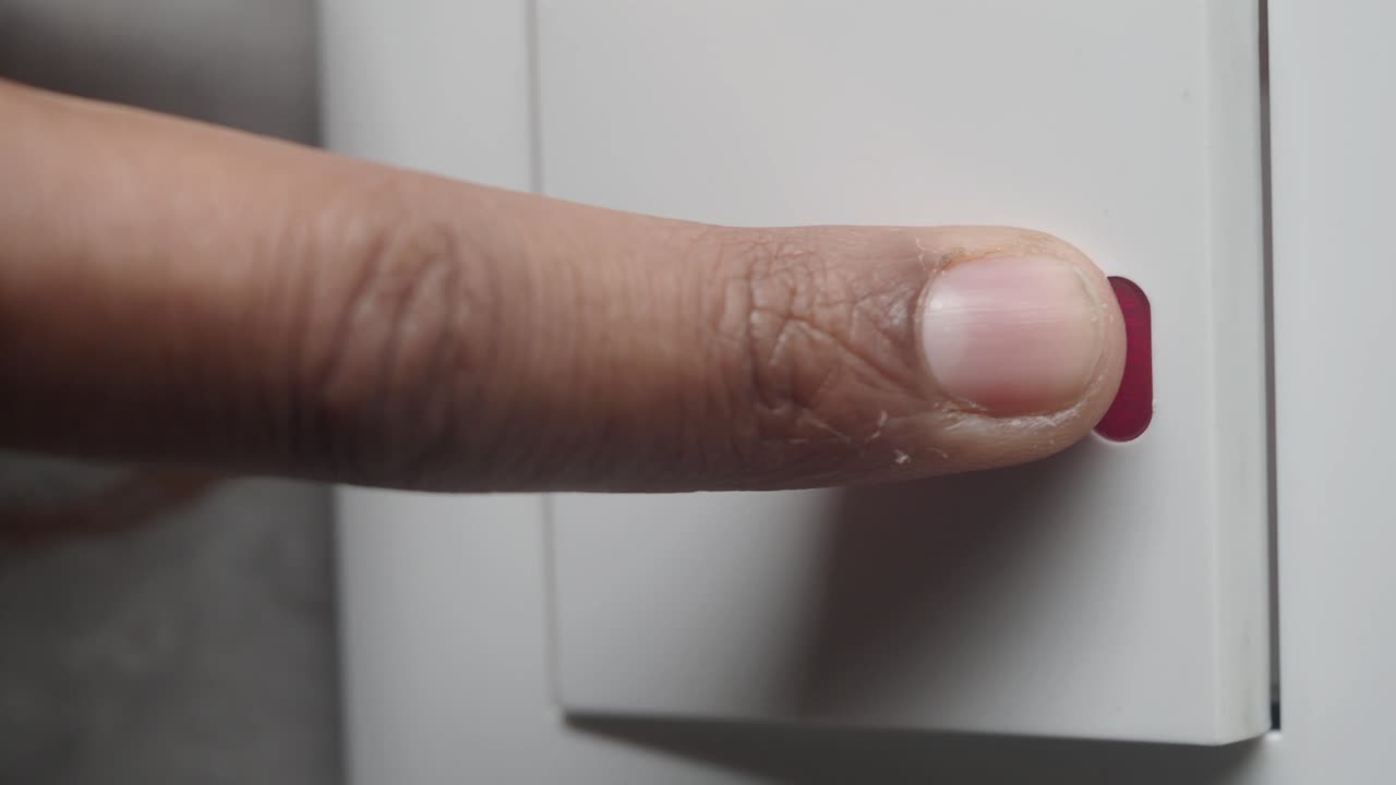 Close-up of a finger pressing a button with a red indicator light
