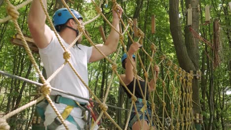 adventure climbing high wire park - people on course in mountain helmet and safety equipment