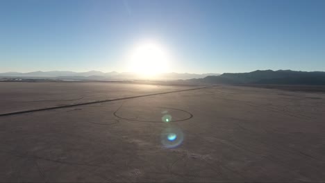 flying over the bonneville salt flats in utah by drone, a causeway and car tracks are visible at sunset