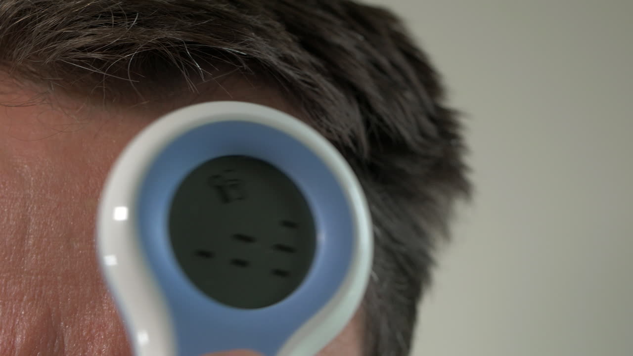 PRIMO PIANO, uomo di mezza età misura la temperatura con un termometro digitale