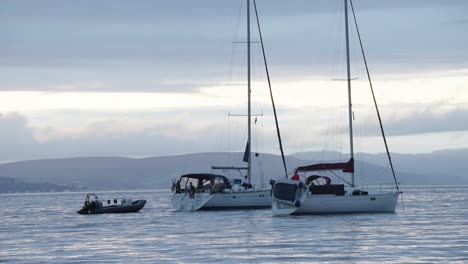two small yachts and a motorised dinghy are moored not far from the coastline