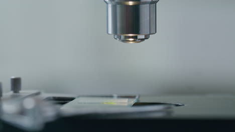 close-up of gloved hands of researcher adjusting microscope slide