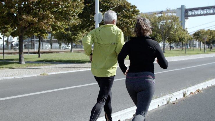 Casal de corredores com mais de 60 anos correndo pela rua