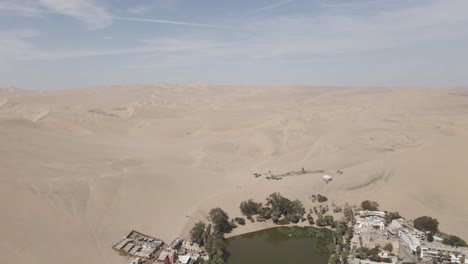aerial drone flies west over huacachina oasis in peruvian desert