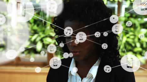 Animation-of-network-of-digital-icons-against-african-american-businesswoman-talking-on-smartphone