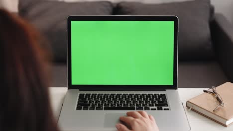 más del hombro de la mujer caucásica mirando la pantalla verde clave de croma. persona de la oficina usando computadora portátil con pantalla de maqueta verde portátil