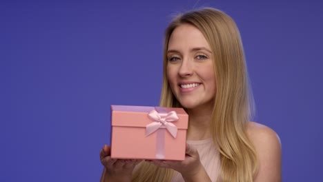retrato de una mujer sosteniendo una caja de regalos rosa en sus manos en pantalla azul