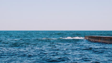 blue seascape background. motion of water waves in the sea. stone dock in seawater. slow motion.