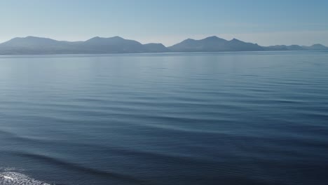 dreamlike misty snowdonia mountain range vista over calm tranquil shimmering blue ocean tide